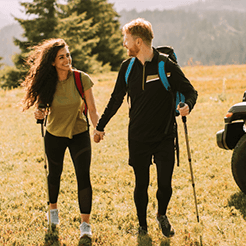 Young couple hiking in mountains next to their Jeep.