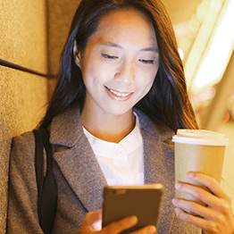 Asian women on her cell phone holding a cup of coffee
