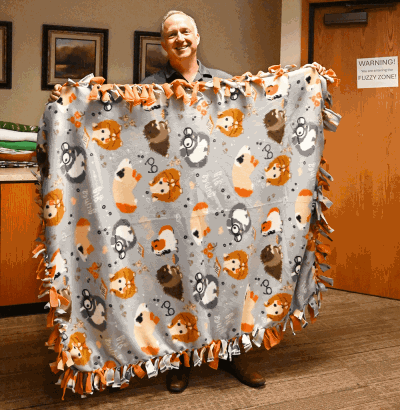 CEO holding up no sew blanket with guinea pigs on it