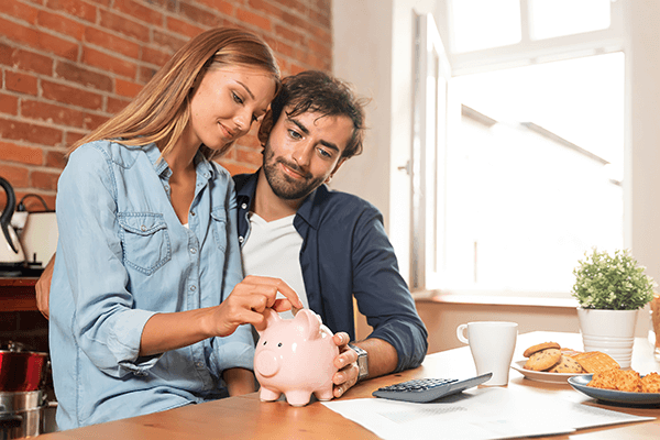 Happy Couple putting money in a piggy bank.