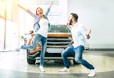 Jumping couple in front of new car