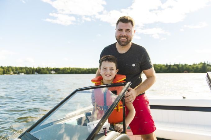 man driving boat with son
