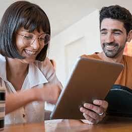 A smiling couple looking at their tablet together.