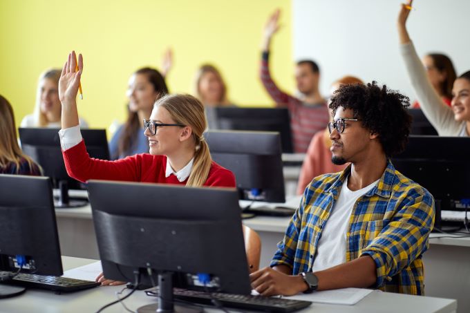 students raising their hands in a computer lab