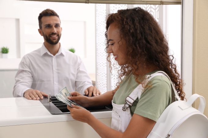 woman member being assisted by male bank teller