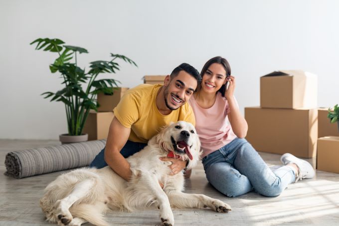 happy young couple unpacking boxes with their dog