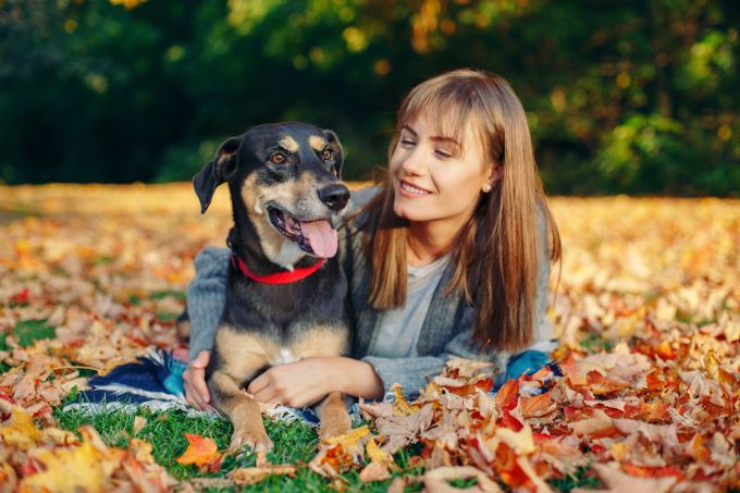 young woman and her dog in a pile of leaves